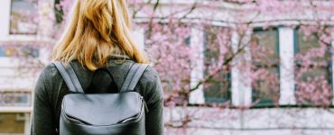 Suche nach einer Studentenwohnung, Frau steht vor einem Haus