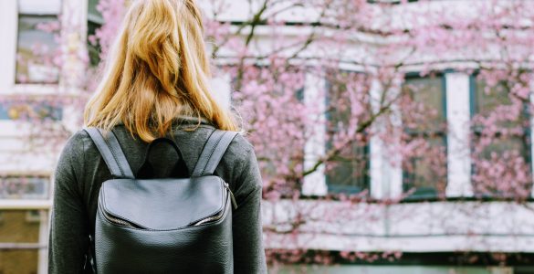 Suche nach einer Studentenwohnung, Frau steht vor einem Haus
